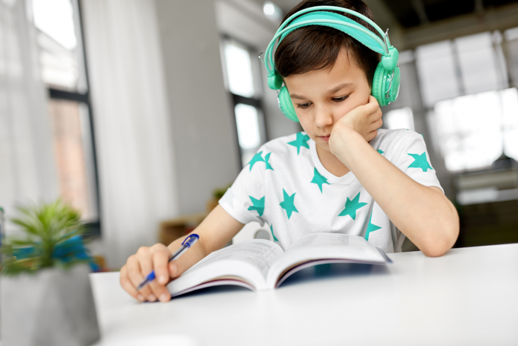 kids with headphones on reading a book.