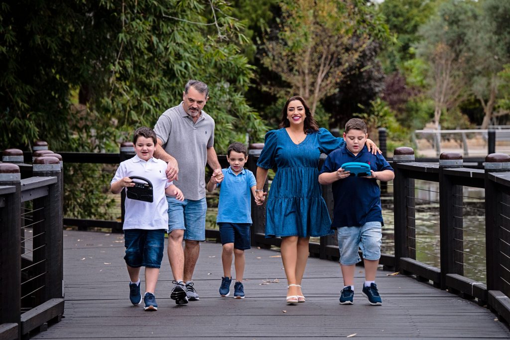 How to maintain your mental resilience and health as tired parents. Mrs Peereboom in a bluue dress with her husband in a grey shirt and her 3 sons walking a bridge.