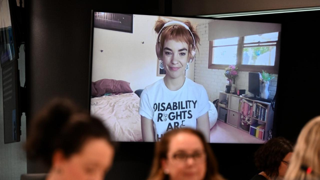 Disability Advocate Chloe Hayden on a computer screen wearing headphones and a white shirt with the words "Disability rights are Hyan rights" 